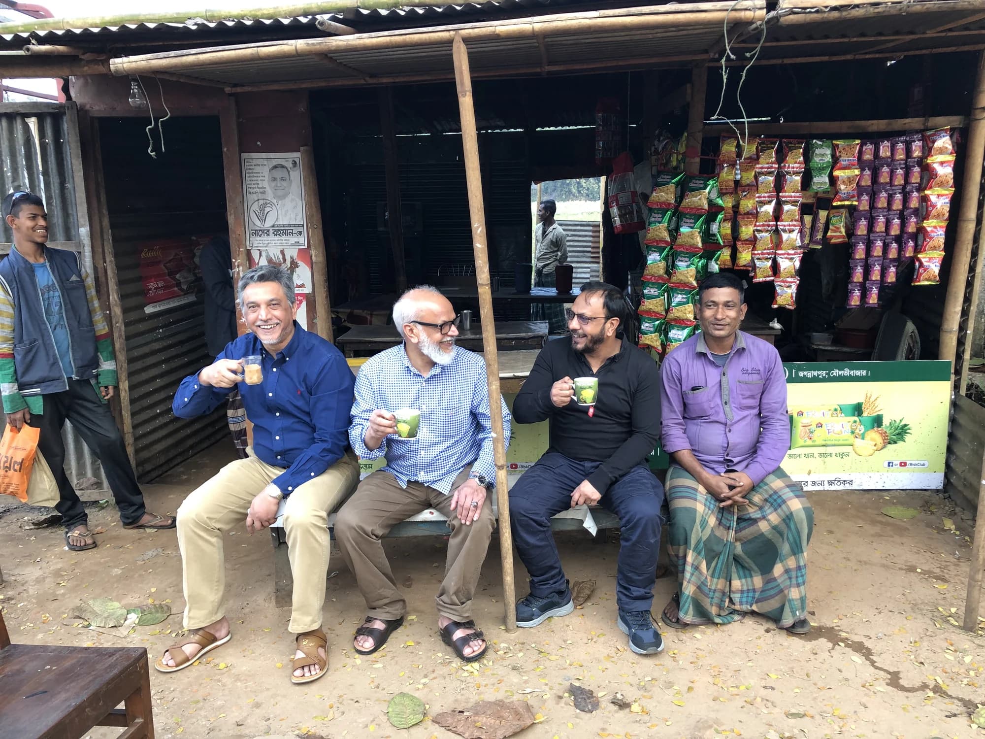Friends sharing cups of tea outside a roadside shop