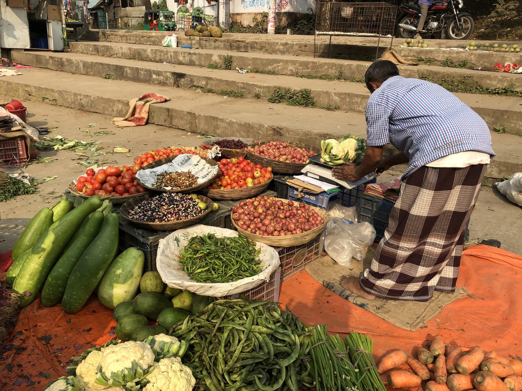 A market stall with tomatoes, gourds, greens and other vegetables